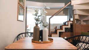 Een eethoek met een houten tafel, twee vazen en stoelen. Een trap is zichtbaar op de achtergrond, leidend naar een verdieping erboven.