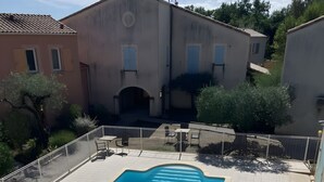 A rectangular swimming pool with a tiled deck, surrounded by a white fence, and adjacent to a building with a tiled roof. - House in Drôme Provençale - Domaine de L'oliveraie (Nyons)