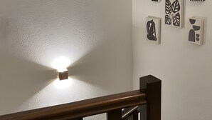 A staircase with a wooden handrail and a wall with abstract art pieces. - House in Drôme Provençale - Domaine de L'oliveraie (Nyons)
