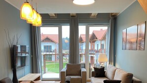 Ein modernes Wohnzimmer mit Essbereich, großen Fenstern und Blick auf einen Wohnkomplex.