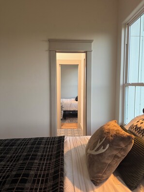 Ein Schlafzimmer mit einem Bett, einem Fenster und einer Tür zu einem anderen Raum.