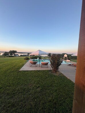 Uma piscina com espreguiçadeiras, um gramado e uma montanha ao fundo.