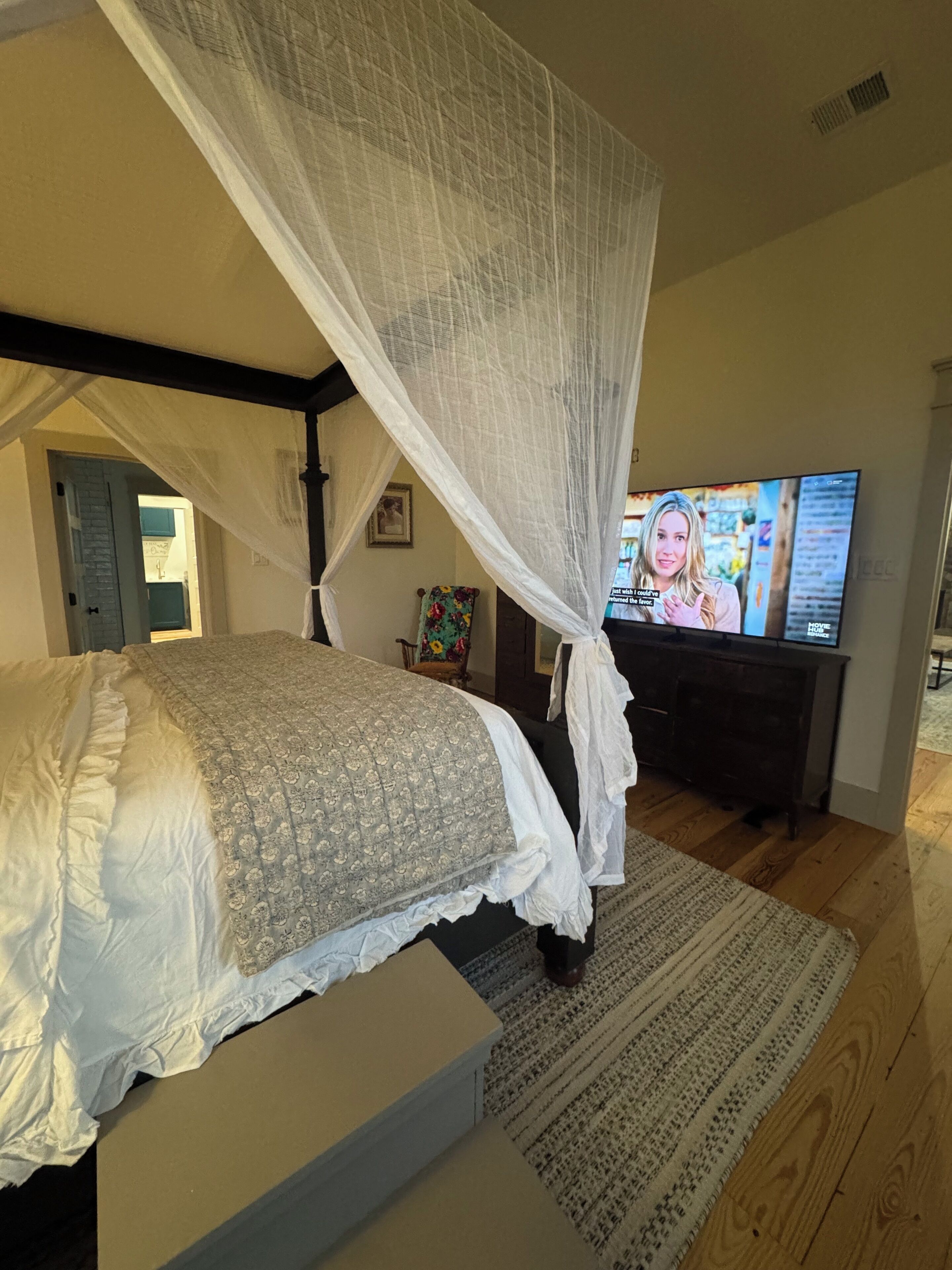 A bedroom with a bed, a television, a dresser, and a window.