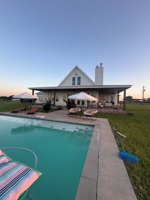 A house with a swimming pool, outdoor seating, and a covered patio.