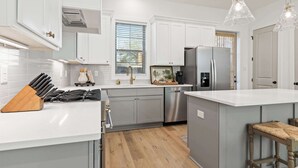 A modern kitchen with white cabinetry, stainless steel appliances, and a wooden island.