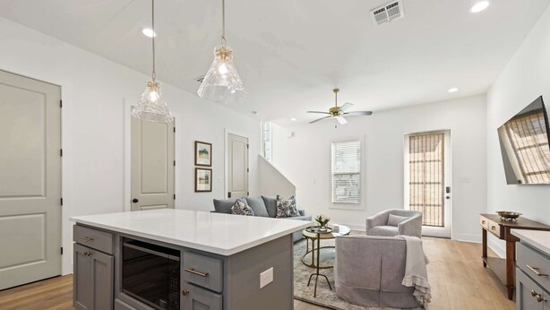 A modern kitchen with grey cabinets, a white countertop, and pendant lighting.