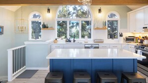 A modern kitchen with a large island, built-in appliances, and a view through a large arched window. - 5min to Beach w Resort Perks! Renovated CLR Home (Corolla)
