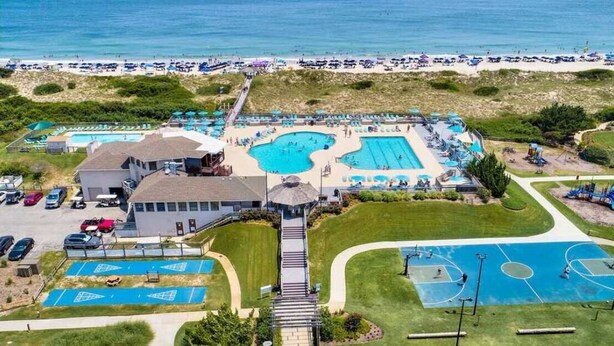An aerial view of a resort with multiple swimming pools, a beach, and a parking area. - 5min to Beach w Resort Perks! Renovated CLR Home (Corolla)
