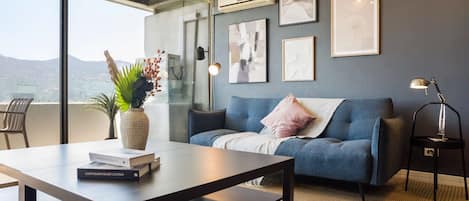Private living room with a blue sectional, curated abstract art, and floor-to-ceiling windows overlooking the mountains.