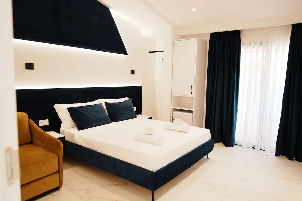 Una habitación de hotel moderna con una cama grande, un sofá, un armario y un escritorio.