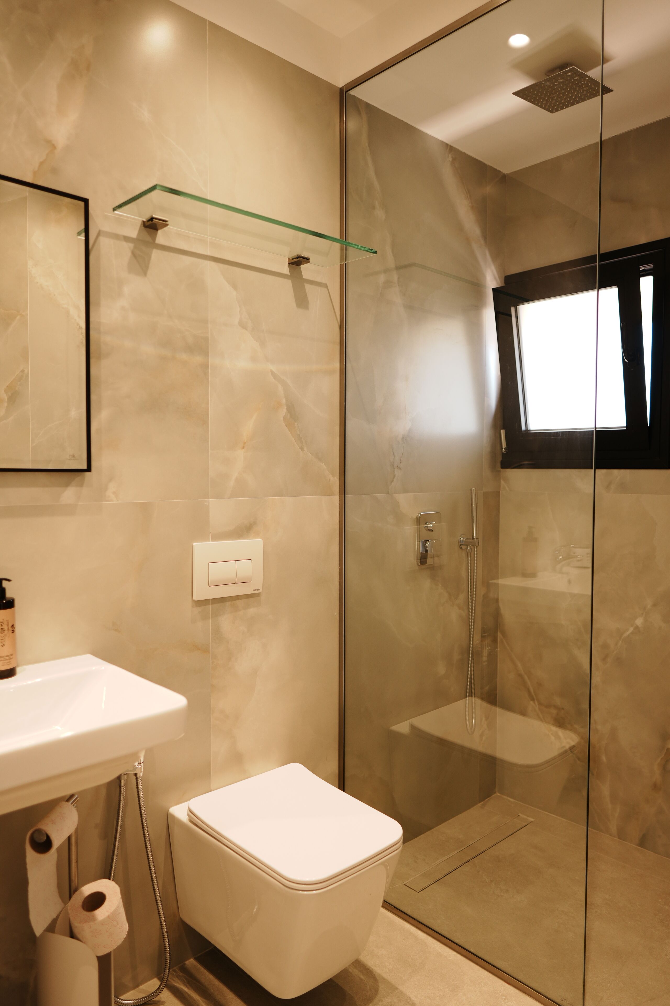 Een moderne badkamer met een douchecabine van glas, een toilet en een wastafel.