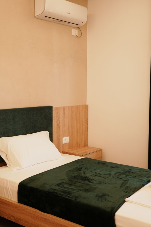 A bedroom with a bed, a wooden nightstand, and a wall-mounted air conditioner. - Villa Solis (Qender Vlore)
