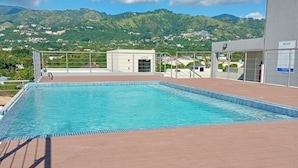 Ein Pool mit Blick auf grüne Hügel und einen klaren Himmel.
