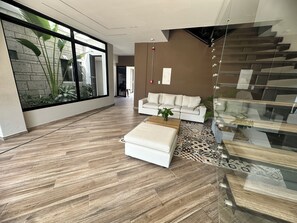 A spacious living area with a white sofa, a coffee table, and a glass staircase. - Edificio Lotus - Torices (Cartagena)