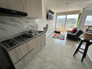A modern kitchen with a gas stove, wooden cabinets, and a built-in TV. - Edificio Lotus - Torices (Cartagena)