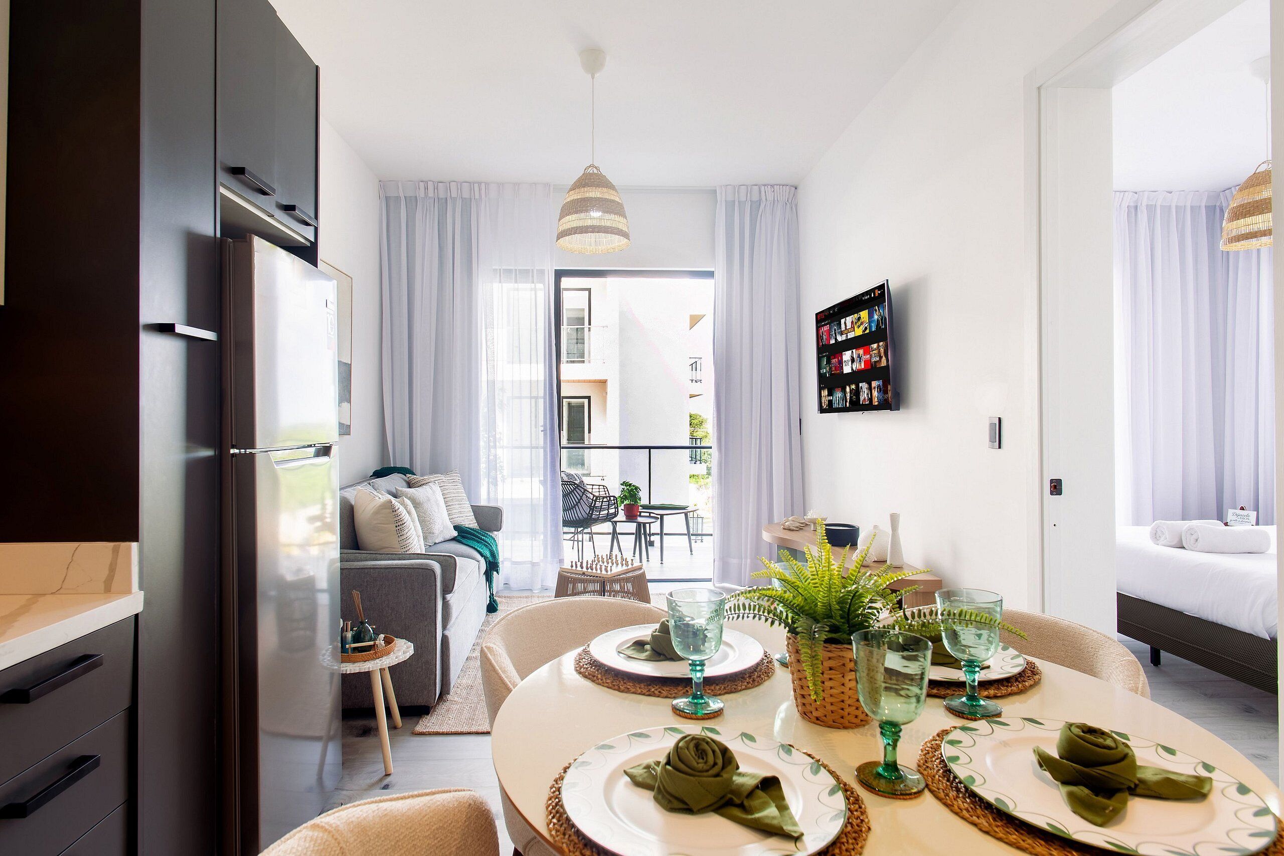 Una habitación de hotel moderna con zona de comedor, sofá y balcón.