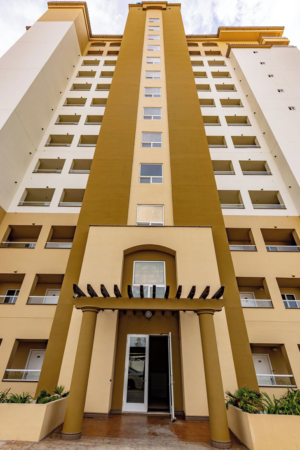 A high-rise building with a central entrance, multiple balconies, and a symmetrical facade.