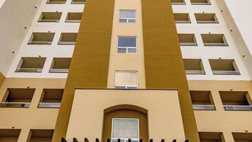 A high-rise building with a central entrance, multiple balconies, and a symmetrical facade.