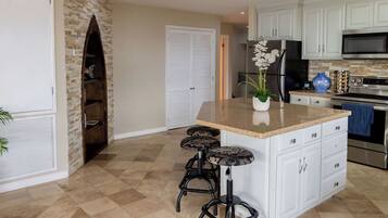 A spacious kitchen with a central island, white cabinetry, and a stone accent wall.