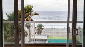 A balcony with a view of the beach and ocean.