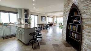A spacious kitchen with a central island, a dining area with a large table, and a cozy seating area.