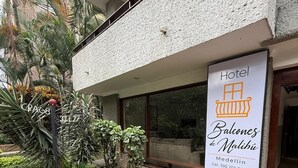 Een hotel genaamd 'Balcones de Malibu' met een naambord waarop de naam en het telefoonnummer staan.