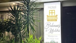 Een hotelschilt met een palmboom en begroeiing ervoor.