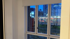 Una habitación con un ventanal grande, paredes blancas y suelo de baldosas.