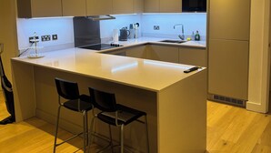 Una cocina moderna con una isla central, taburetes de bar, horno empotrado y un refrigerador de acero inoxidable.