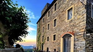 Un edificio de piedra con varias ventanas, una puerta y mesas al aire libre.