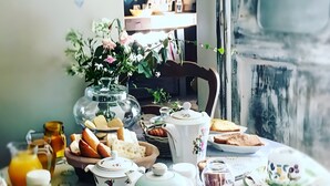 A table set with various kitchenware and food items, a vase with flowers, and a heart-shaped decoration on the wall. - Suite Nostalgie-Casa Ghjunca (Rapale)