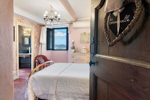 A bedroom with a bed, a dresser, a chair, and a window with a view. - Casa Ghjunca Guesthouse – Ciucciarella Room (Rapale)