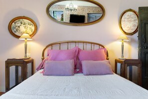 A bedroom with a bed, two bedside tables, two lamps, a mirror, and a door. - Casa Ghjunca Guesthouse – Ciucciarella Room (Rapale)