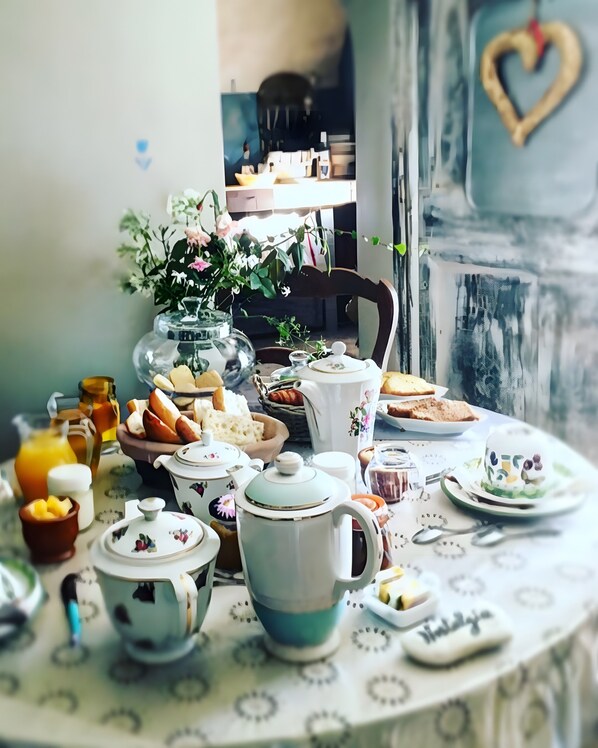 A table set with various kitchenware and food items, a vase with flowers, and a heart-shaped decoration on the wall.