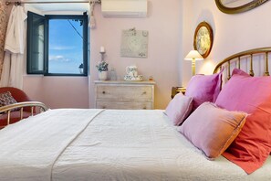 A bedroom with a bed, a dresser, a nightstand, a lamp, a mirror, and a window with curtains. - Casa Ghjunca Guesthouse – Ciucciarella Room (Rapale)