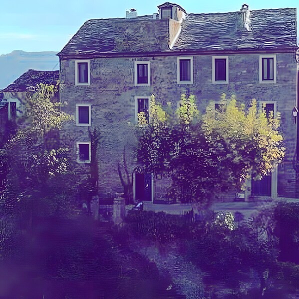 A stone building with multiple windows and a chimney.