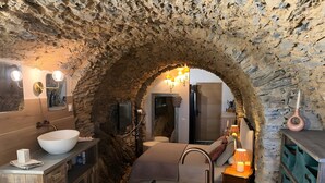 A rustic bathroom with a stone arch, a large white sink, a bathtub, and a wooden vanity. - Ciucciarella Apartment in Casa Ghjunca Guesthouse (Rapale)