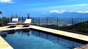 A swimming pool with a wooden deck, lounge chairs, and a view of mountains. - Ciucciarella Apartment in Casa Ghjunca Guesthouse (Rapale)