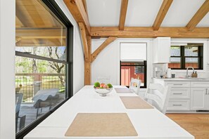 A modern kitchen with white cabinets, a wooden ceiling, and a dining area with a table and chairs. - Rose Cabin at Highland Peaks Retreat (Highlands)