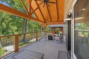Une terrasse couverte avec vue sur une rivière, des sièges d’extérieur et un ventilateur de plafond.