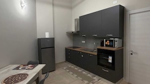 A modern kitchen with a dining area, featuring a built-in oven, microwave, and a large cabinet. - Dante Urbano Loft (Torino)