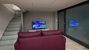 A modern living room with a red sofa, a flat-screen TV, and a staircase. - Dante Urbano Loft (Torino)