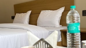 A hotel room with two beds, a tray with breakfast including eggs, a coffee cup, and a water bottle. - Hotel Abline The Oaks (Rishikesh)