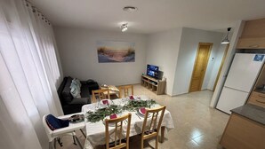 A compact living space with a dining area, kitchenette, and a TV. - Renovated apartment with pool and 2 minutes from the beach. Quiet location (Els Muntells)