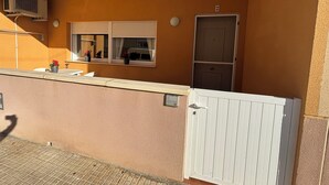 A balcony with a white door, a window with a white blind, and a wall-mounted air conditioning unit. - Renovated apartment with pool and 2 minutes from the beach. Quiet location (Els Muntells)