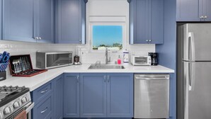 Une cuisine moderne avec des meubles bleus, des appareils en acier inoxydable et une fenêtre offrant une vue agréable.