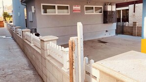 Un bâtiment sur lequel est apposée une pancarte indiquant « VÉHICULES ENLEVÉS », doté d’une entrée fermée par un portail et d’un chemin en béton menant à une porte.