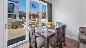 Uma área de refeições com uma mesa posta para quatro pessoas, vista para a varanda externa e uma bandeira americana.