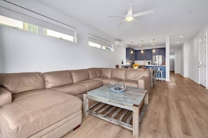 A modern living room with a sectional sofa, a rustic coffee table, and a kitchen in the background. - RMB III: Island Paradise 2Br Deck (Sleeps 10-14) (San Diego)