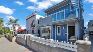 A modern two-story house with a balcony, a garage, and a white picket fence.